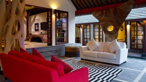 A modern living room with a white sofa, red armchairs, and a unique wooden sculpture. - Escape to Bali Villa – Ubud’s Premier Sanctuary 1000 (Bali)