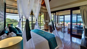 Un dormitorio con cama con dosel, un balcón con vistas al mar y un televisor.