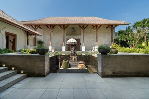 Un bâtiment traditionnel avec un toit en tuiles, une statue centrale et un élément décoratif aquatique.
