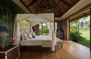 Une chambre spacieuse dotée d’un lit à baldaquin, d’une télévision et offrant une vue sur un jardin luxuriant.