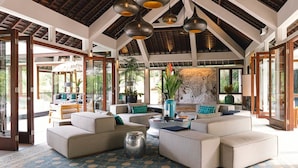 A spacious living area with multiple seating arrangements, large windows, and a high ceiling with exposed beams. - 5 Star Villa in Bali, Minutes from the Beach, Bali Villa 1026 (Bali)