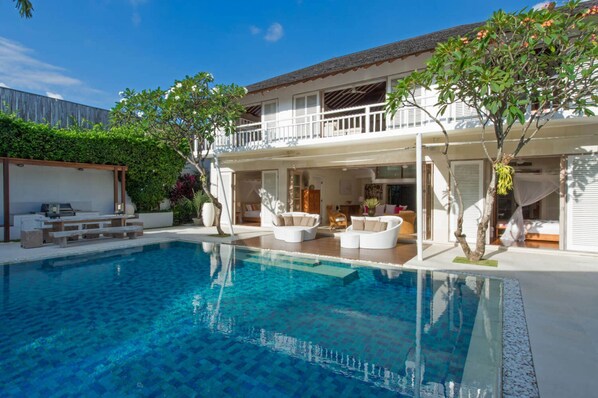 A modern house with a swimming pool, outdoor seating, and a balcony.