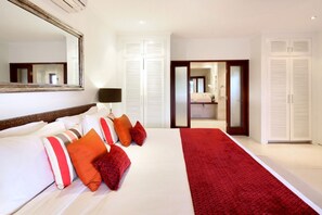 Une chambre d’hôtel avec un grand lit, un tapis rouge et un miroir au mur.
