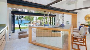 Une cuisine moderne dotée d’un îlot central, de grandes fenêtres et offrant une vue sur l’extérieur.