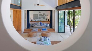 Un salon moderne doté d’une fenêtre circulaire, d’un ventilateur de plafond et d’un mur avec des lambris en bois.