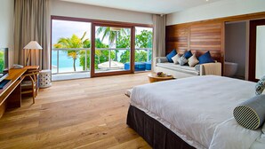 Une chambre d’hôtel avec un grand lit, un bureau avec une télévision et un balcon donnant sur l’océan.