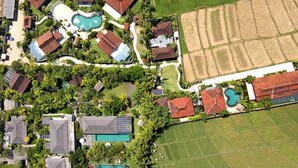 An aerial view of a residential area with multiple houses, a swimming pool, and a large field. - Secluded Comfort, Steps from the Beach – Bali Villa 1096 (Bali)