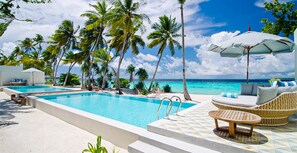 A pool area with two swimming pools, lounge chairs, and umbrellas. - You and Your Family will love this Ultra Luxury Villa in the Maldives with 24/7 Concierge (Baa Atoll)