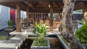 Un espace extérieur aménagé, abrité et doté de mobilier en bois, ainsi que d’un bassin à carpes koï.