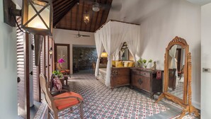 Une chambre à coucher avec un lit à baldaquin, une commode en bois, un miroir et un mur en pierre.