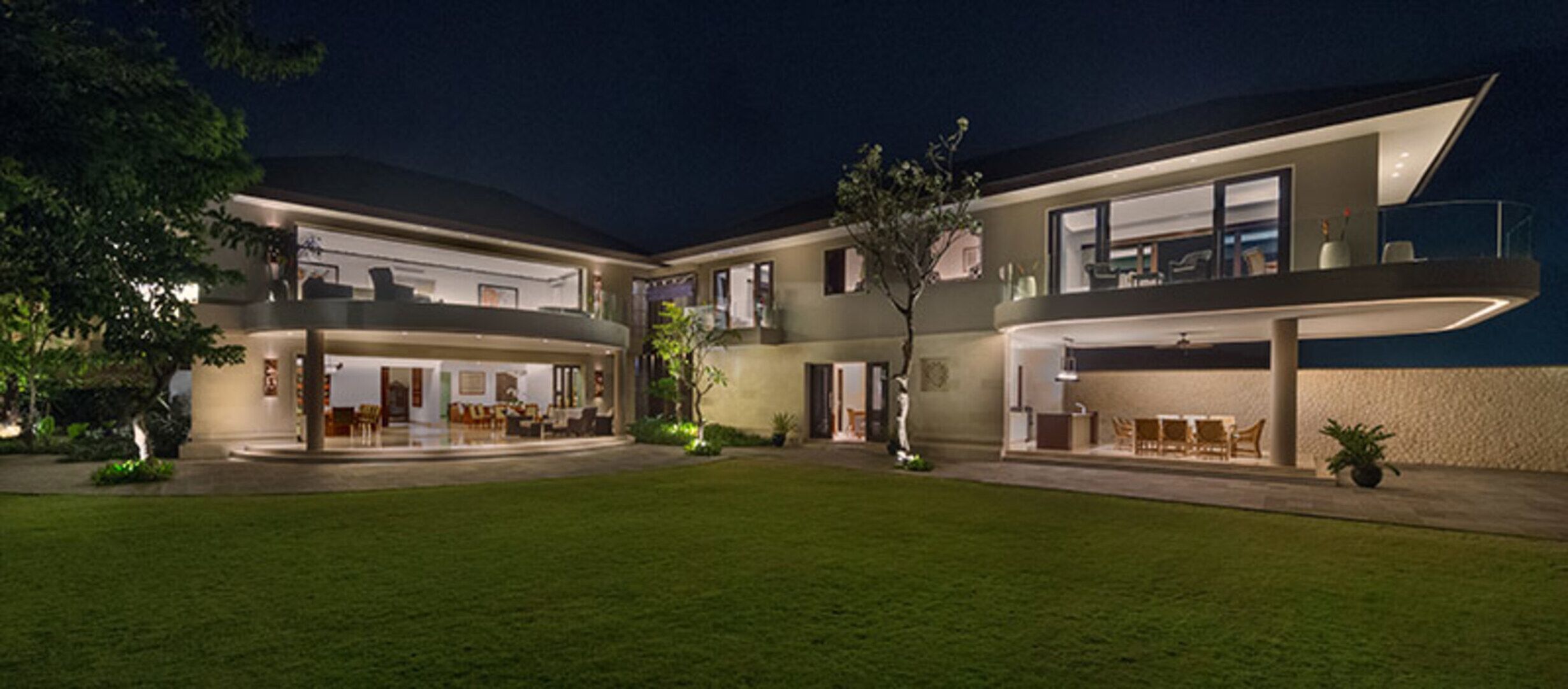 Une maison moderne à deux étages, dotée d’un vaste espace extérieur, d’un balcon et d’une entrée bien éclairée.