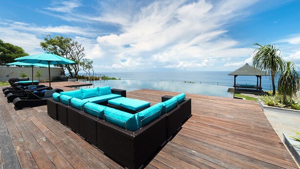 Eine Holzterrasse mit Pool, Liegestühlen und einem Pavillon mit Blick auf ein Gewässer.