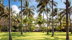 Een tropisch resort met palmbomen en een gebouw met rieten dak.