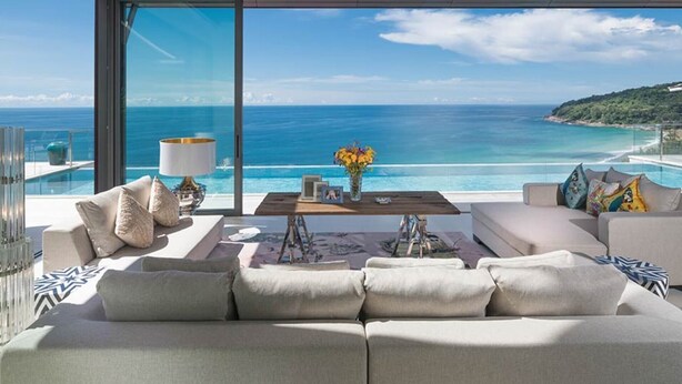 A modern living room with a large window overlooking a beach and ocean.