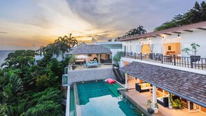 Ein modernes Haus mit Swimmingpool, überdachter Terrasse und Meerblick.
