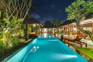 A swimming pool with lounge chairs and umbrellas, surrounded by tropical plants and wooden structures. - Serene luxury in lush gardens, Bali Villa 1124 (Bali)