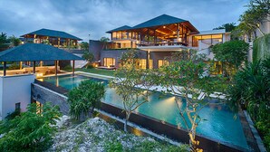 A modern resort with a large swimming pool, multiple outdoor seating areas, and a well-maintained garden. - Experience Ultimate Luxury by the Beach, Bali Villa 1129 (Bali)