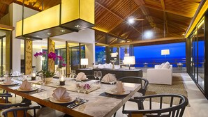 A modern dining area with a long table set for a meal, surrounded by chairs. - Experience Ultimate Luxury by the Beach, Bali Villa 1129 (Bali)