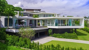 Una casa moderna de varios niveles con piscina, exuberante vegetación y césped cuidado.