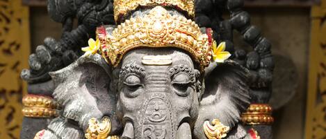 A detailed statue of an elephant with intricate golden decorations and a sign in the background.