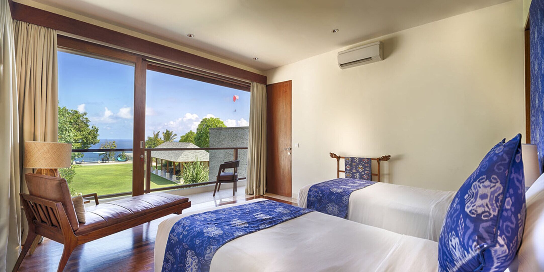 Habitación de hotel con dos camas, un balcón y vistas al mar, además de una silla.