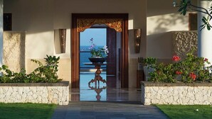 Una entrada imponente con una piscina reflectante, muros de piedra y vistas al mar.