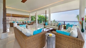 Amplia sala de estar con muebles de mimbre, un ventanal con vista al mar y decoración tropical.