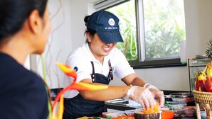 A person serving food in a kitchen area with a window in the background. - Luxury Family Retreat with Private Chef, Koh Samui Villa 1001 (Koh Samui)