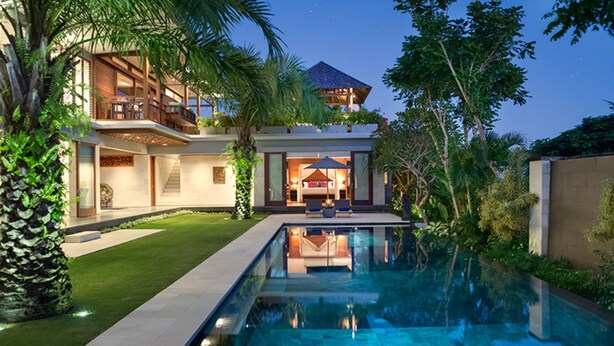 Una casa moderna de dos pisos con piscina, abundante vegetación e interior bien iluminado.