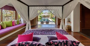 Un dormitorio con una cama grande, vista a una piscina y un balcón con cojines de colores.