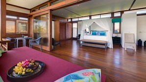 Un dormitorio amplio con una cama grande, un comedor con una mesa y sillas, y vistas a través de un ventanal.