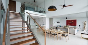 Un interior moderno con una escalera de madera, un comedor y una sala de estar con una pared de acento roja.