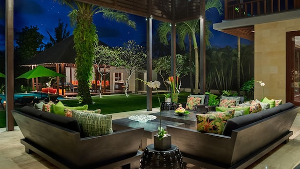 Un espace de détente extérieur moderne, doté d’une piscine, de sièges et d’une décoration de style tropical.