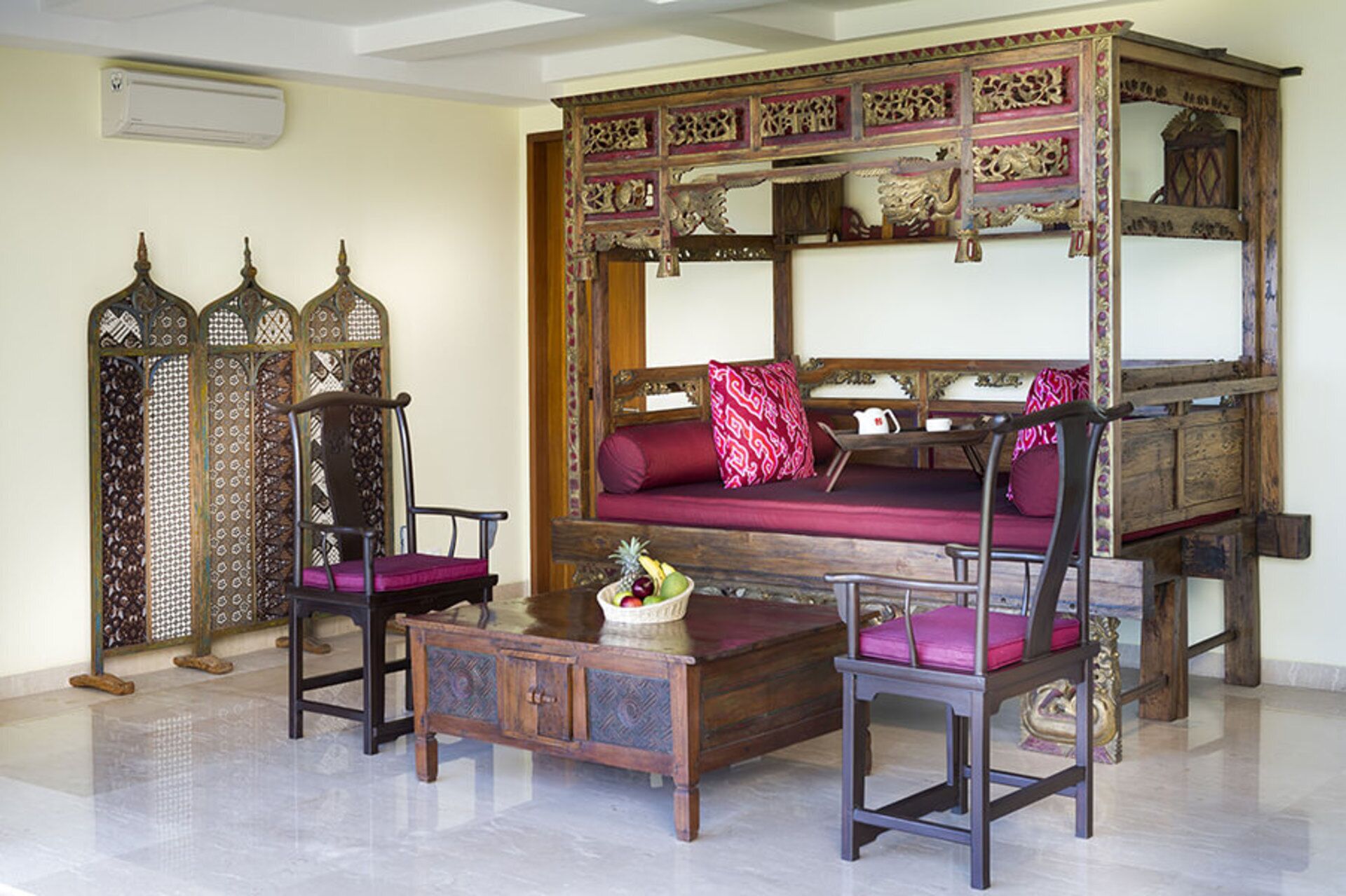 Una habitación tradicional con una cama de madera, dos sillas, una mesita pequeña y un aparador decorativo.
