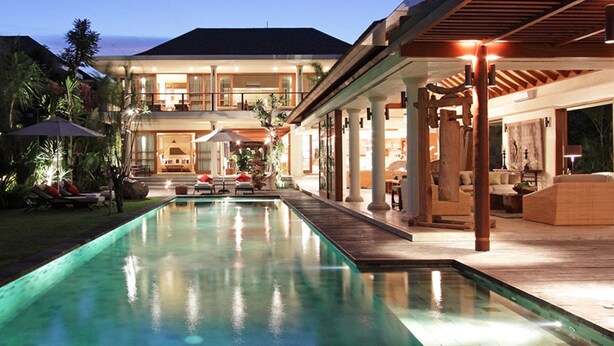 Ein großer Pool mit Holzterrasse, Sitzgelegenheiten im Freien und einer überdachten Terrasse.