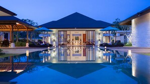Ein modernes Haus mit Swimmingpool, Sitzgelegenheit im Freien und einem gut beleuchteten Innenraum.