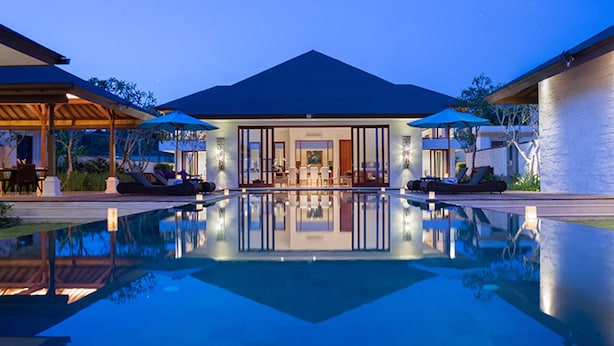 Ein modernes Haus mit Swimmingpool, Sitzgelegenheit im Freien und einem gut beleuchteten Innenraum.
