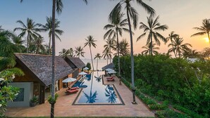 Un resort con piscina, palmeras y un atardecer.