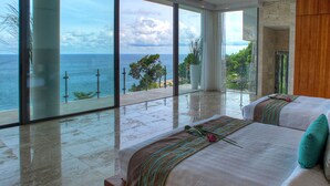 Une chambre dotée d’une grande porte vitrée donnant sur un balcon avec vue sur la mer.