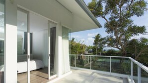 A modern balcony with a glass door leading to a room with a bed and a wooden floor. - Modern Beachside Escape with Private Pool – Bali Villa 1108 (Bali)