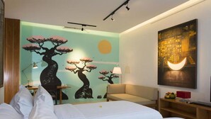A hotel room with two beds, a sofa, a nightstand with a lamp, a wall with a tree mural, and a painting of a crescent moon. - Modern Beachside Escape with Private Pool – Bali Villa 1108 (Bali)