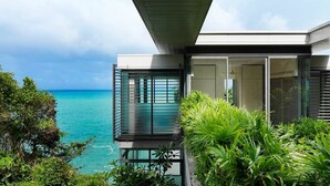 Een modern huis met grote glasramen met uitzicht op een turquoise zee.