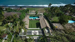 An aerial view of a resort with a swimming pool, lounge area, and ocean view. - Rent a Luxury Villa in Bali Close to the Beach, Bali Villa 1130 (Bali)