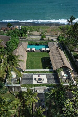 Eine Luftaufnahme eines Resorts mit Schwimmbad, Liegebereich und Meerblick.
