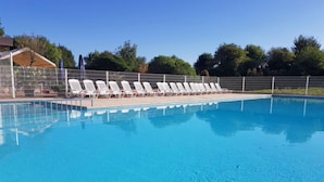 Une piscine avec des chaises longues blanches et une clôture.