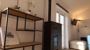 Un salon moderne avec une étagère en bois, un meuble noir, un canapé blanc et une lampe sur pied.