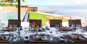 Ein Esstisch, gedeckt für eine Mahlzeit, mit Blick auf das Meer.