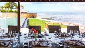 A dining table set for a meal with a view of the ocean.