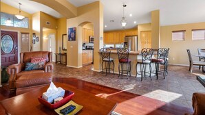 Amplia sala de estar con una mesa de comedor de madera, sofá de cuero y una cocina al fondo.