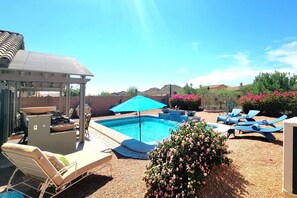 Relax by the spacious pool surrounded by comfortable lounge chairs and lush greenery.
